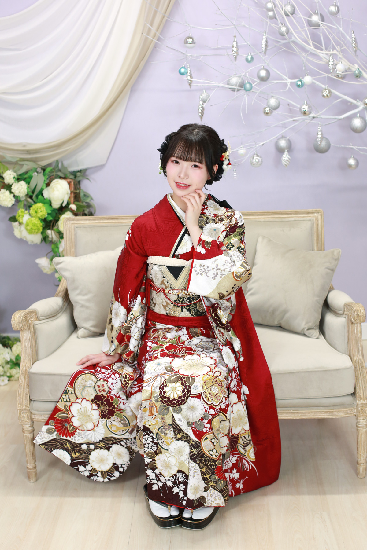 赤い振袖で白いソファに座ったスタジオ撮影